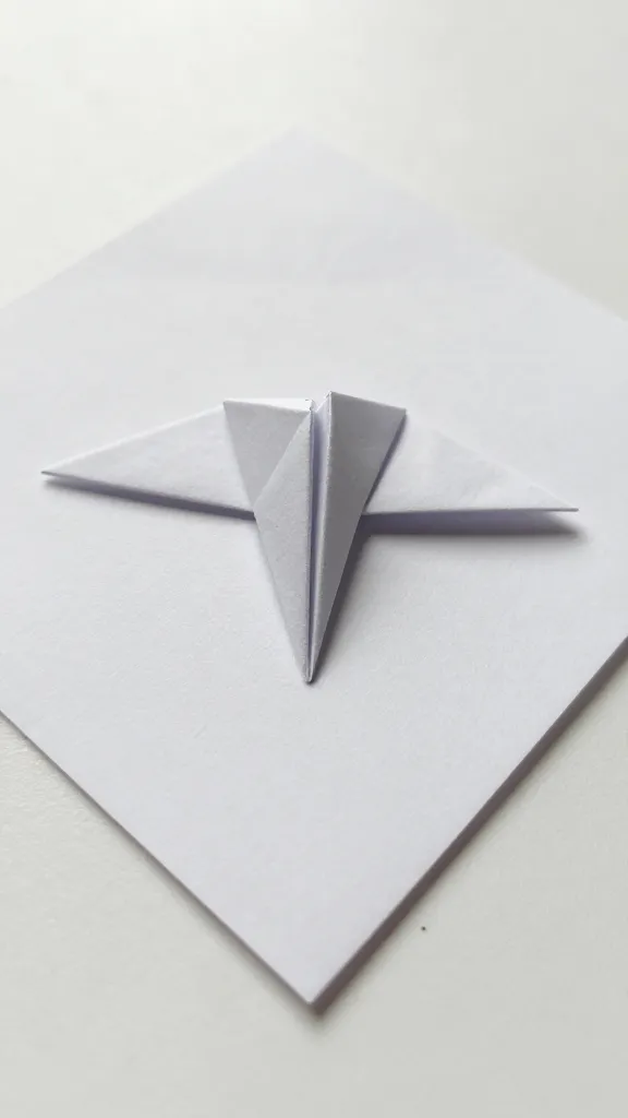 Closeup of single square sheet transitioning into folded origami sculpture vertex