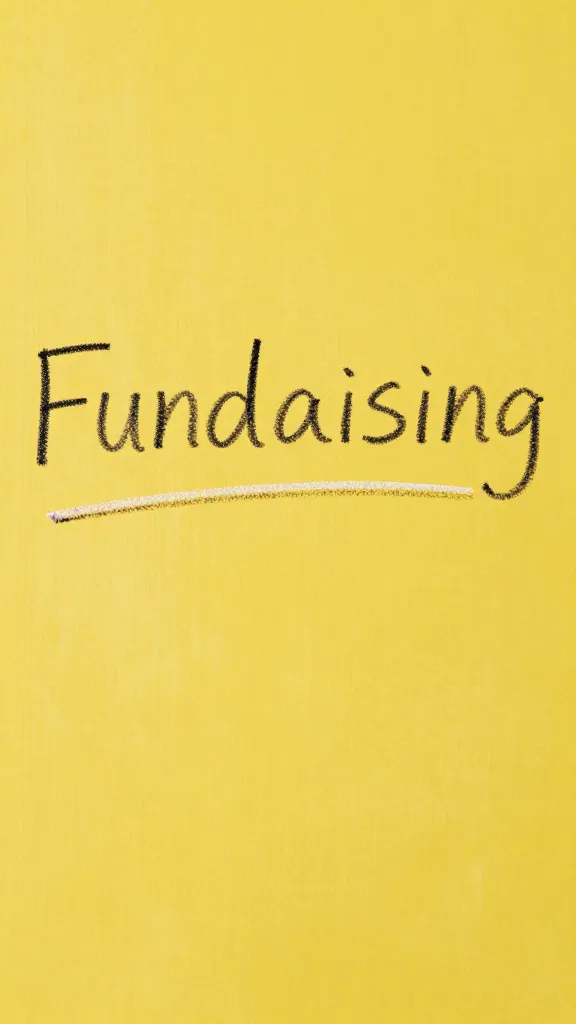 Closeup of a bright yellow chalkboard with a precise fundraising target written in chalk