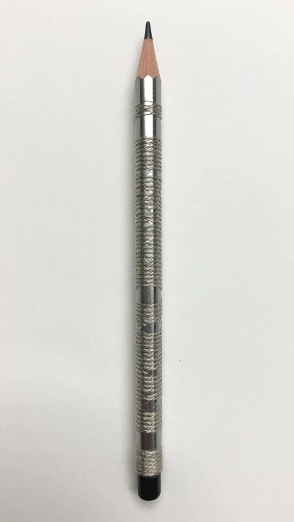 Closeup of a single neatly wrapped yarn-wrapped pencil on plain surface