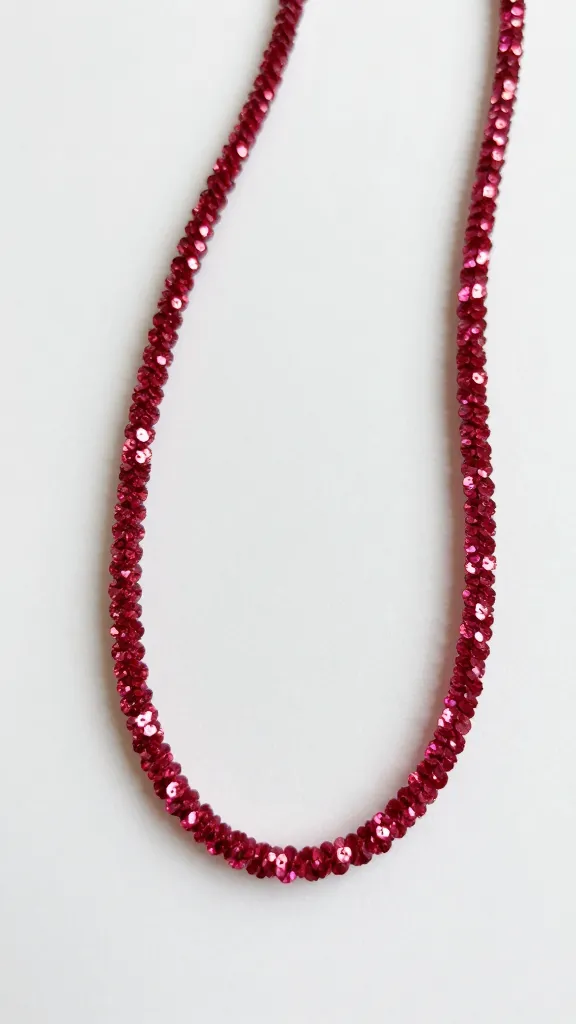 Closeup of a single glittery pipe cleaner necklace on a white backdrop