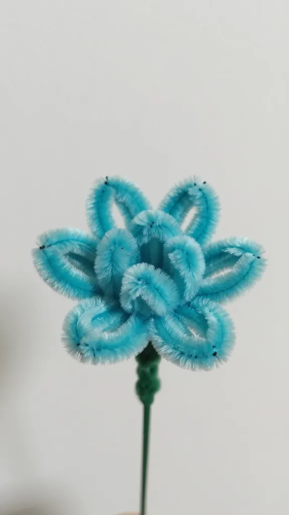 closeup of a single turquoise pipe cleaner flower bud in soft focus