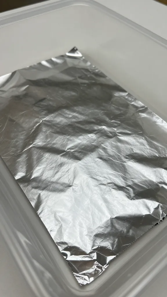closeup of foil sheet with crinkled edges in a plastic storage box