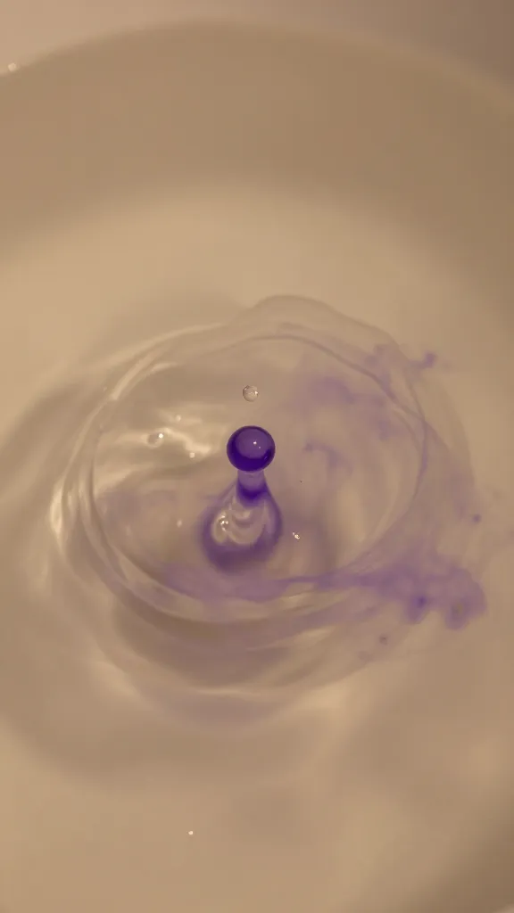 closeup of warm water with purple dye wisps around a tiny droplet